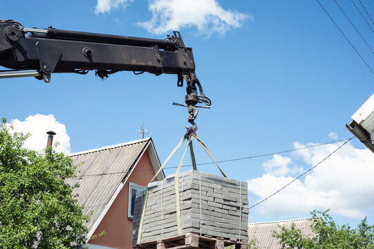 Unloading paving slabs from a truck. Men unload paving slabs using a manipulator. Workers unload building materials from a large machine.