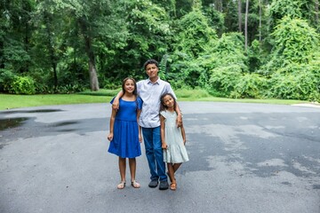 Fototapeta premium Three siblings standing outside their home hugging and embracing for a picture