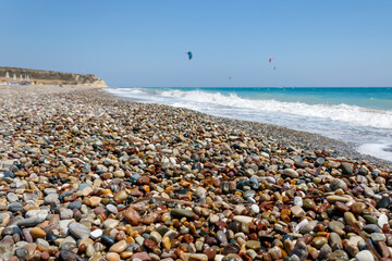 Fototapeta na wymiar Sea beach with colorful wet pebbles and good wind for kitesurfing