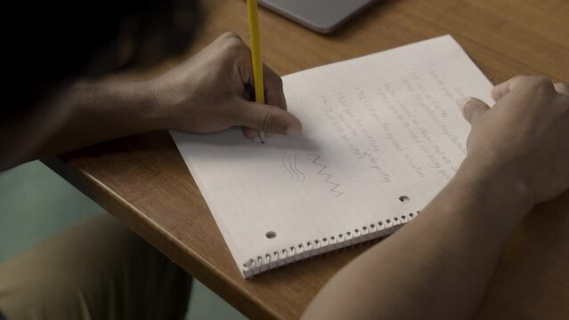 Detail frame of a Native American male student drawing designs on his notebook during graphic design class.