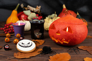 Halloween pumpkins on the background of a dark wall with ghosts, bats, spiders, candles, pumpkins, leaves. Selective focus.