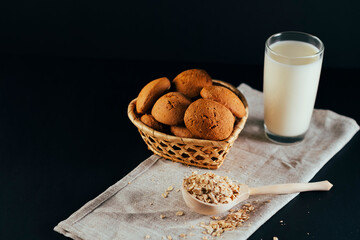 Oatmeal cookies with a glass of milk on a napkin on a black background. The concept of a healthy breakfast
