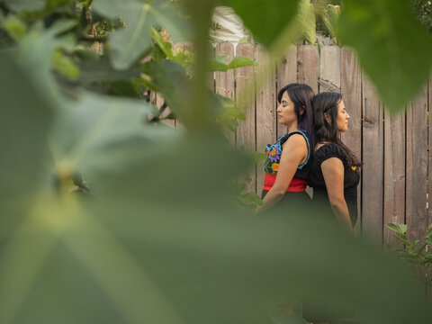 Indigenous twin sisters standing back to back