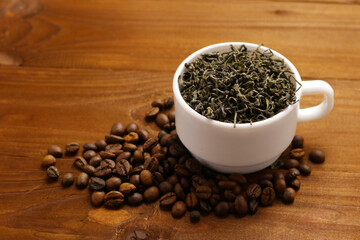 Coffee grains and tea leaves in cup on table