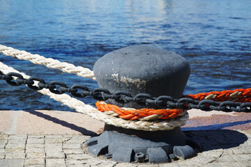 Bollard with ship ropes on the background of the sea.