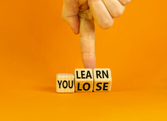 We learn or lose symbol. Concept words We learn and We lose on wooden cubes. Businessman hand....