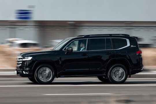 Toyota Land Cruiser 300 rides on the city highway. Black premium SUV on the city street in motion.