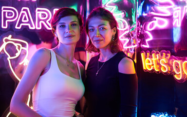 Image of two beautiful women in an amusement park in a room with neon light. Entertainment concept
