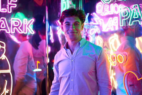 Image of an adult male in an amusement park in a room with neon light. Entertainment concept.