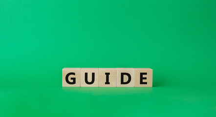 Guide symbol. Wooden cubes with word Guide. Beautiful green background. Guide concept. Copy space.