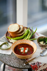 Traditional Ukrainian borscht with sour cream in a clay bowl.