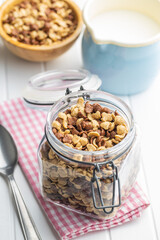 Breakfast cereal flakes in jar on checkered napkin.