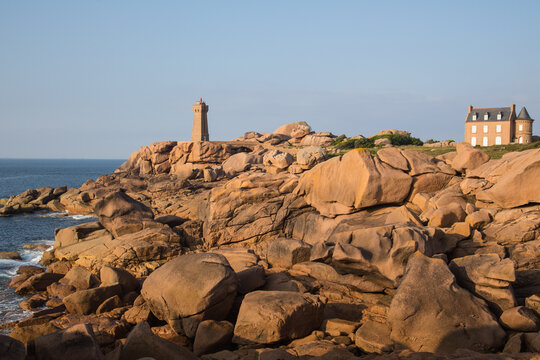 Lighthouse Men Ruz and museum Maison du Littoral towering the extraordinarily and beautifully colored stones and fantastically shaped rock formations at sunset-pink granite coast in Brittany, France