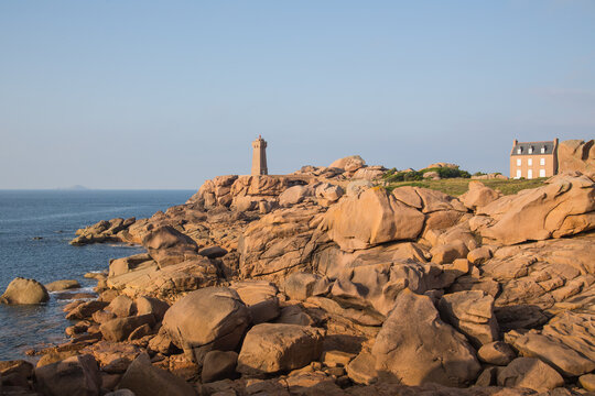 Lighthouse Men Ruz and museum Maison Littoral towering the extraordinarily colored stones and fantastically shaped rock formations at the Atlantic Ocean-pink granite coast, Brittany, France