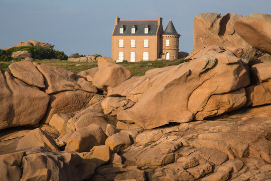 Museum Maison du Littoral towering the extraordinarily beautifully colored stones and fantastically shaped rock formations at sunset- the famous pink granite coast in Brittany, France