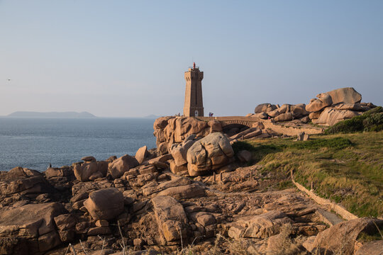 The lighthouse Men Ruz with bridge towering the extraordinarily colored stones and fantastically shaped rock formations along the walking trail - the famous pink granite coast in Brittany, France