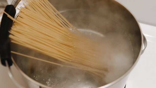 The cook throws pasta into boiling water. Cooks spaghetti for shrimp pasta.