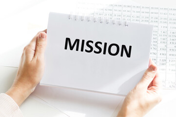 Business, Internet and technology concept. Mission text on a notebook in the hands of a girl at the table.