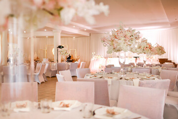 Decorated wedding banquet hall in classic style. Restaurant interior for banquet, wedding decor with white and pink flowers.