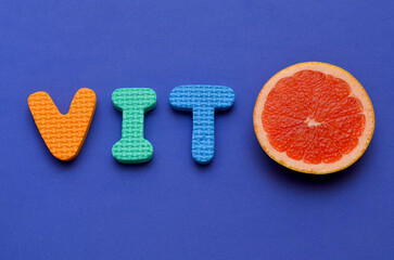 cutaway red grapefruit and the inscription vitamin, colorful background