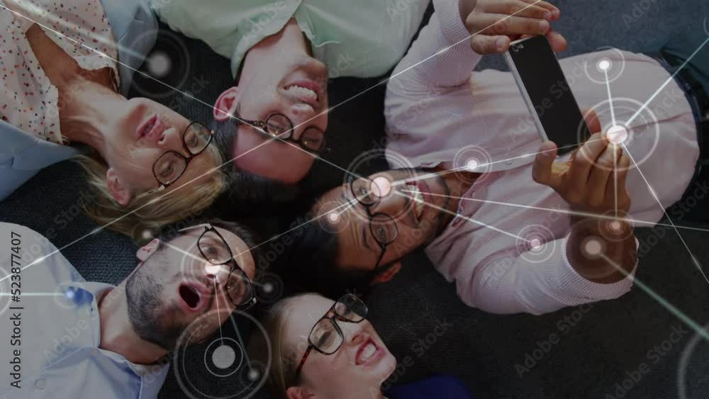Poster animation of dots connecting with lines over man taking selfie with coworkers while lying on floor
