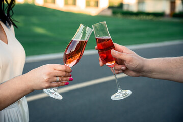 female and male hands with glasses of wine or red champagne, check