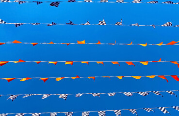 Many lines rows of isolated flag pennats chains garlands racing symbol against clear blue cloudless summer sky - Zandvoort, Netherlands - obrazy, fototapety, plakaty