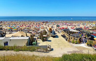 Zandvoort, Netherlands - August 12. 2022: View from dunes on crowded dutch north sea city beach on sunny summer weekend