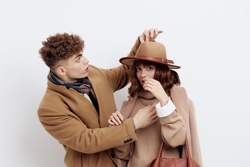 a cute couple is standing on a white background, wearing a coat. The man gently touches the top of...