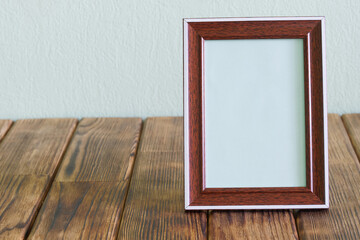 Blank empty photo frame for photos, pictures or announcements on a rustic vintage pine plank table. Textured pale green background. Filled interior element. Copy space.