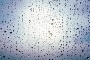 Raindrops on window glass, cloudy weather, background, texture.