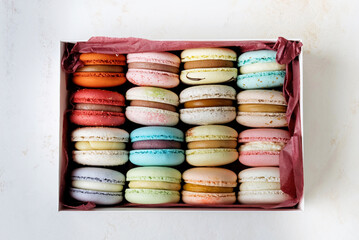 Colorful macaroons in a gift box on a white table.