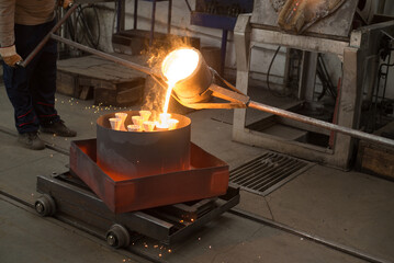 Workers molding objects in the foundry, pouring melted metal in molds