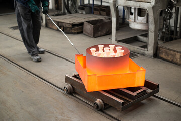 Workers molding objects in the foundry, pouring melted metal in molds