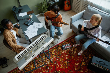 Top view at band of young musicians playing instruments together in cozy home studio
