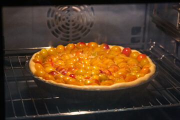 Raw Mirabelle plum tart not yet baked in backing pan in the oven.