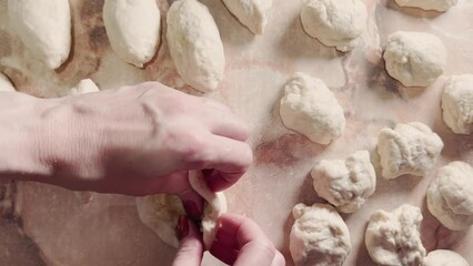 Women's hands make dough pies in home kitchen.