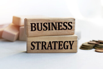 The inscription BUSINESS STRATEGY on wooden cubes isolated on a light background. Concept word forming on wooden cube. Business, economics and finance concept.