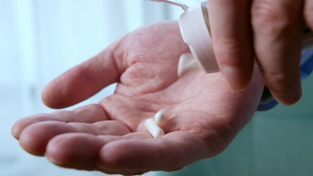 Adult man holding painkiller pills on male hand pouring many capsules from meds bottle taking medicine, old elderly grandmother health care, pharmacy and treatment concept, close up view