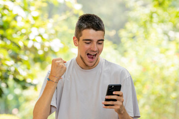 excited young man celebrating looking at mobile phone