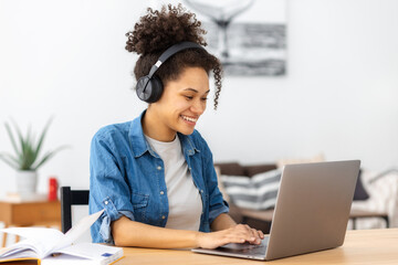 Smiling woman student online learning at home. Beautiful African American female student using...