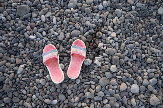 Top view of pink flip-flops on pebbles. Pebble beach. Summer vacation.