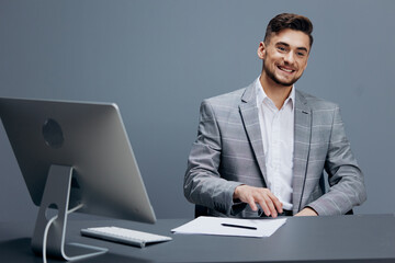manager in a gray suit sits in front of a computer technologies