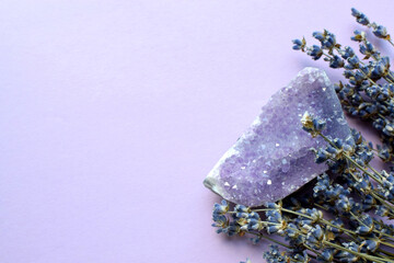 A beautiful amethyst druse with a dry bouquet of lavender on a lilac background. Magic amulets.