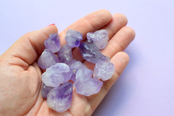 Beautiful semi-precious stones in a female hand. A woman holds purple amethyst crystals in her hands. Magic stones for meditation.