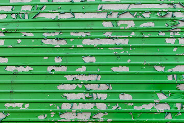 Peeling green paint in messy pattern on corrugated metal surface