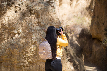 Mujer turista tomando fotografías con una cámara profesional en un cañón disfrutando de sus vacaciones en perú. Concepto de personas, hobbies y tecnología.