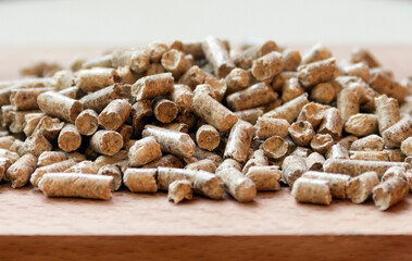 Front view of wooden pellets placed on the wooden board, selective focus.
