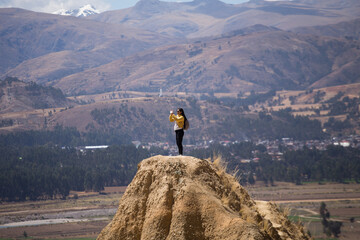 mujer turista disfrutando de sus vacaciones en lo más alto de una montaña con montañas al fondo....