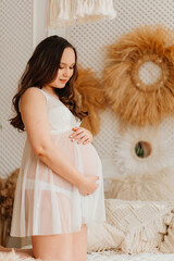 a pregnant woman in white peignoir on bed. sexy clothes for pregnant. 